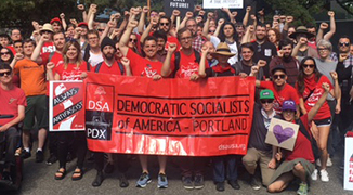 Image of Democratic Socialists, behind a red banner, wearing red and holding up left fists in the air.