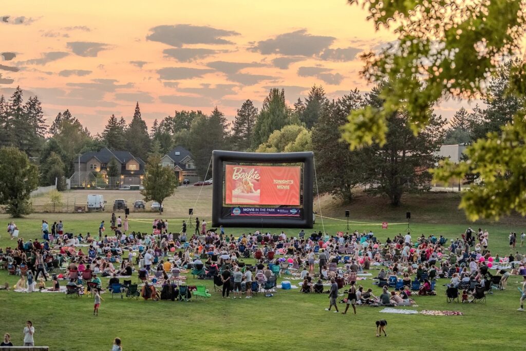 a movie screening at a large open grassy area in a park